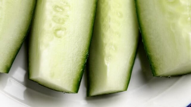 Fresh juicy cucumber slices on kitchen plate. Vegetable salad ingredient. Macro shot. Rotation