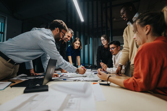 A multicultural group of business people collaborates around a table, engaged in an energetic discussion. The team analyzes documents, sharing creative ideas and strategizing solutions for a