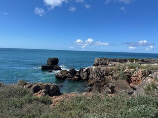 Cascais, Portugal - May 19, 2025: Scenic coastal view featuring rocky shoreline and vibrant blue ocean under a clear sky, ideal for travel and hotel marketing imagery