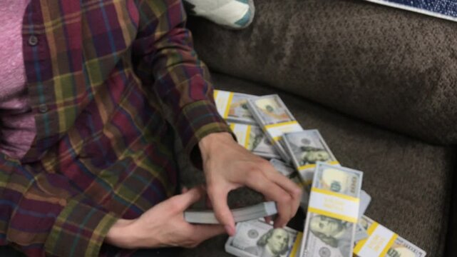 Young Woman Counts Stacks of Cash $100 Bills
