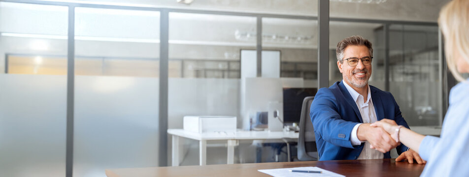 Latin bank worker man shaking hand with client, recruit female employee or business partner after signing a contract. Group of people satisfied with results of team work together. Banner, copy space