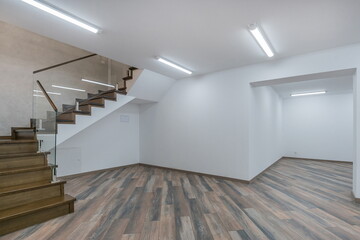 The hall of the first floor of a private house. White finish, brown laminate, stairs with dark wood...