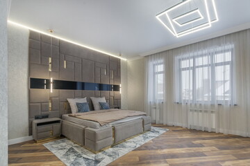 Modern interior design of a bedroom in a country house. Exclusive wall decoration at the head of the bed. Stylish furniture.