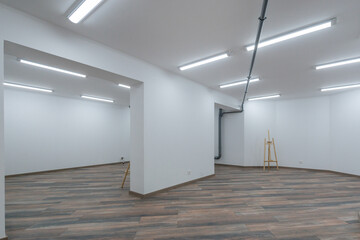 Spacious room with a fine finish, unfurnished. Laminate flooring, white walls, ceiling lights.