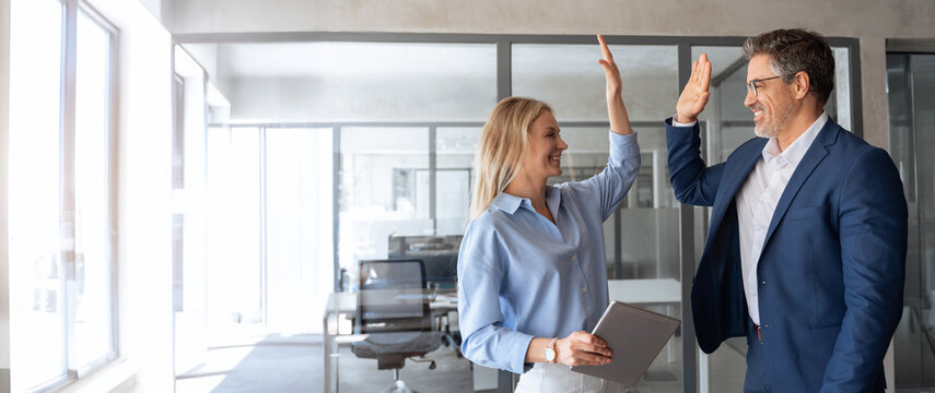 Happy smiling successful Hispanic businessman and young European professional business woman celebrating achieving performance, outcomes in work giving high five standing in office. Banner, copy space