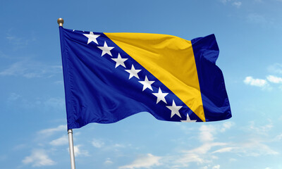 Flag of Bosnia and Herzegovina with stars and golden triangle fluttering in blue sky symbolizing...