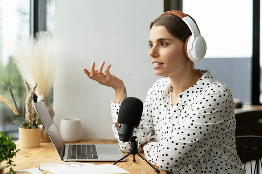 Podcaster creating online content with microphone and laptop