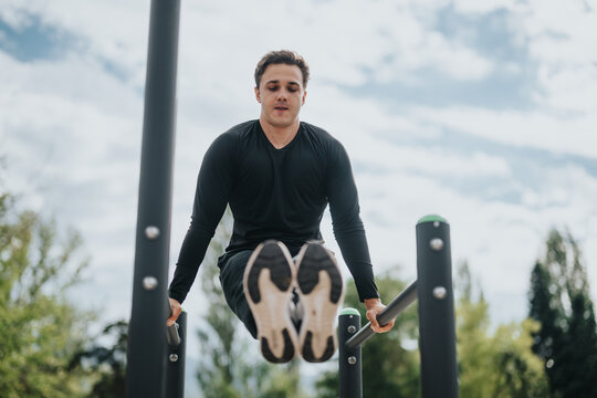 A man practices calisthenics on parallel bars in an outdoor park setting. The image depicts fitness, determination, and an active lifestyle in a natural environment under a clear sky.
