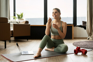 Fitness woman eating yogurt and relaxing after home workout
