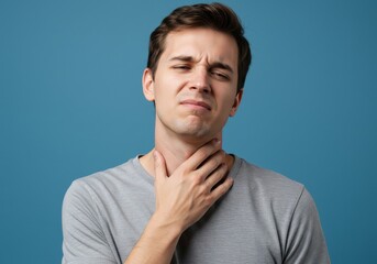 Portrait of a white man touching his neck and showing signs of discomfort or pain, suggesting sore throat, inflamed lymph nodes, or neck strain. Neutral gray background. Health and illness theme.