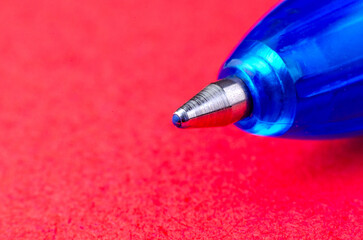 Blue ballpoint pen macro close-up on vibrant red background