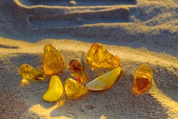 Baltic amber in white, yellow, and honey shades shines warmly in sunset light on Kołobrzeg's summer beach.