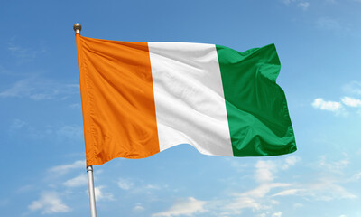 National flag of Ivory Coast with vertical orange, white, and green stripes waving in the sky