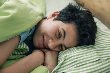 Teenager girl waking up and smiling in her bed in the morning