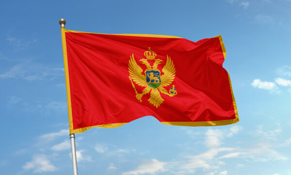 Montenegro national flag with golden border and eagle emblem waving proudly in the sky - Powered by Adobe