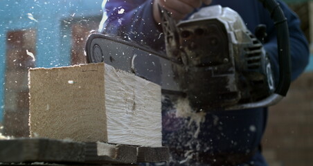 Close-up of chainsaw cutting through wooden plank, wood chips and shavings scattering in super slow motion, 800 fps, powerful carpentry work