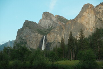 Yosemite National Park in California’s Sierra Nevada mountains green foliage on sunny day waterfall evening view
