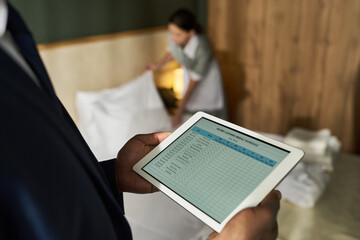 Business person managing hotel staff using tablet technology for housekeeping operations in hotel...