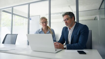 Two partners, team of professional business people working, discussing work sitting at desk. Mature focused senior mentor leader man showing young woman manager project on laptop in office. Copy space - Powered by Adobe