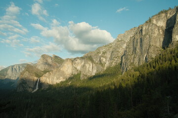 Yosemite National Park in California’s Sierra Nevada mountains green foliage on sunny day waterfall evening view