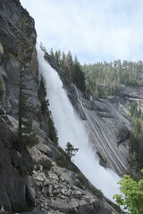 Scenery with granite cliffs, greenery, cascading waterfalls , puffy clouds and blue skies at...