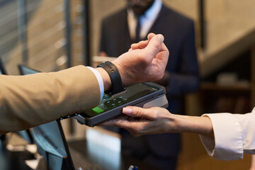 Close-up of a contactless payment transaction at a checkout counter, showing hands and payment device, indicating secure and convenient transaction technology