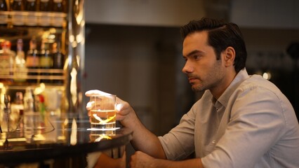 Sitting smart man drinking alone of cocktail Old fashioned waiting friends or couple at bokeh lighting at luxurious beverage counter nightclub at pub and restaurant on Friday meeting night. Vinosity.