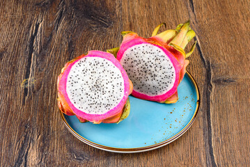 Halves of fresh and juicy pitahaya on a blue plate.