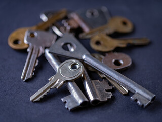 A pile of different keys for different locks and doors on a dark background.