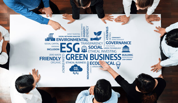 A diverse group of business professionals engaging in discussion about ESG and green business practices, emphasizing teamwork and sustainability concepts around a table. Amity