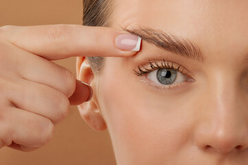 Blepharoplasty. Woman touching eyelid skin and pointing to the wrinkles on the upper eyelid,...