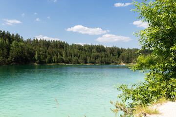 turquoise water lake surrounded by pine trees, view into the distance.It's a beautiful summer day.background, a place to copy