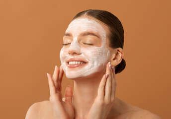Face skin care concept. Happy lady posing with facial mask, standing with closed eyes and smile...