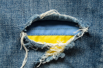 Flag of Ukraine seen through a hole in denim, symbol of freedom, democracy