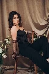 Obraz premium Confident woman in black sitting sideways on chair