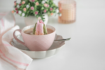 Hot chocolate in pink mug with whipped cream and tulip flower shaped marshmallows.