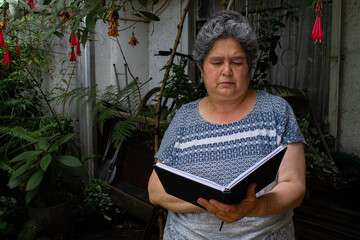 Mujer leyendo tranquilamente un libro en el patío de su casa.