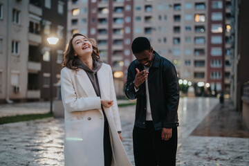 Fototapeta premium Two friends share a cheerful laugh outdoors in a modern city environment, embodying friendship, joy, and connection during an evening in the urban landscape.