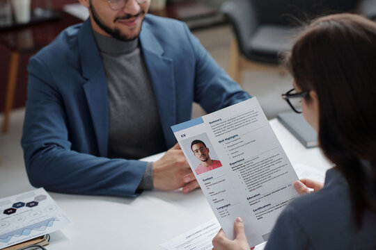 Over shoulder view of young HR manager reading CV while interviewing candidate for job position copy space