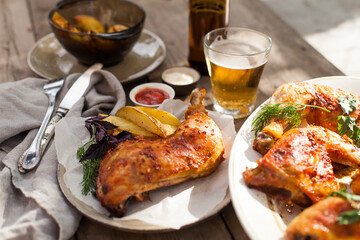 Top-down view of pub food: baked chicken drumsticks, rustic fries, sliced pickles, sauces, and beer. Cozy and casual atmosphere. Perfect for menus, blogs, or food delivery visuals