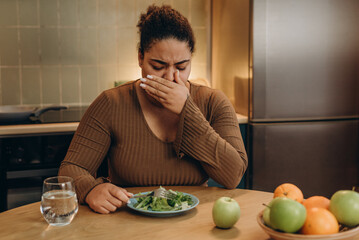 Female suffers from eating disorder and feeling nausea at the kitchen