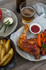 Top-down view of pub food: baked chicken drumsticks, rustic fries, sliced pickles, sauces, and beer. Cozy and casual atmosphere. Perfect for menus, blogs, or food delivery visuals