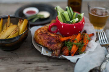 Top-down view of pub food: baked chicken drumsticks, rustic fries, sliced pickles, sauces, and beer. Cozy and casual atmosphere. Perfect for menus, blogs, or food delivery visuals
