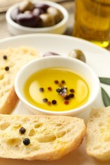 Slices of bread with oil, spices and olives on wooden table, closeup