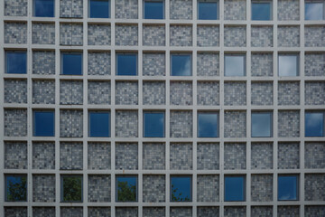Close-up view of a building facade featuring a repetitive grid pattern of square sections, each...