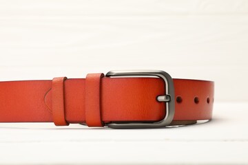 One orange leather belt on white table, closeup