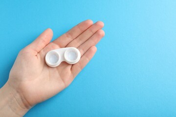 Woman with contact lenses on light blue background, top view. Space for text