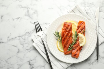 Seafood. Tasty grilled salmon served with cutlery, rosemary and lemon on white marble table, flat lay. Space for text
