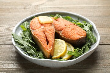 Seafood. Tasty salmon steaks, arugula and lemon on wooden table, closeup