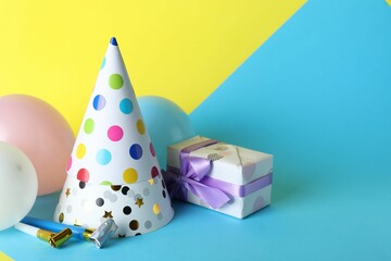 Beautiful party hats and other festive decor on color background, space for text